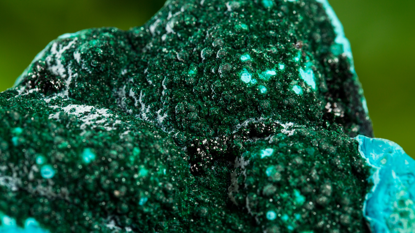 Macro shot of a raw malachite crystal with vibrant green hues and natural textures.